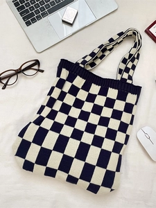 Knitted checkerboard tote bag for women with black and white grid pattern on a desk
