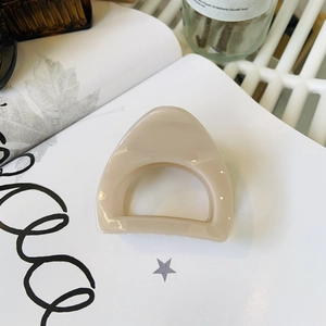 Beige medium hollow hair claw clip for high ponytail on white book background