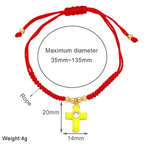 Detail of red cord bracelet with yellow enamel cross pendant and gold beads