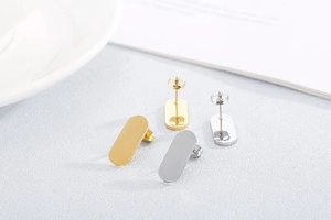 Detail of gold and silver rectangular stud earrings with backings on a white plate