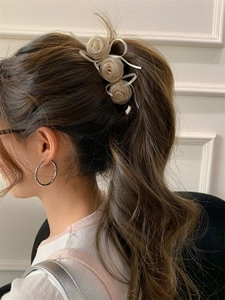 Détail de trois pinces à cheveux rose crème en tissu sur une queue de cheval, vue arrière