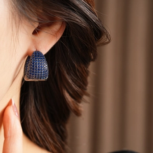 Detailed view of silver hoop earrings featuring pavé-set dark blue cubic zirconia stones