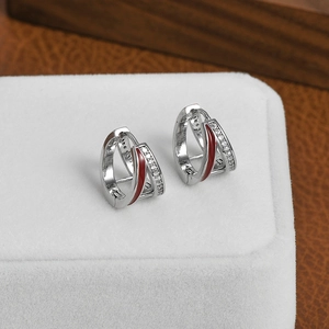 Silver micro-set zircon hoop earrings with red enamel detail on a wooden display