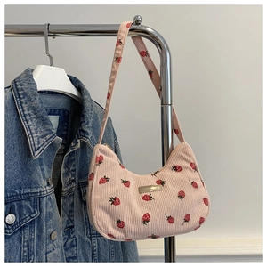 Detailed close-up of pink corduroy underarm bag with strawberry print on metal stand