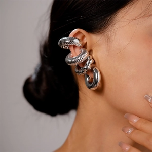 Macro detail of silver metal ear cuffs set featuring spiral, woven and polished textures