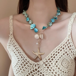 Detail of blue bead necklace featuring golden starfish and shell charms on model