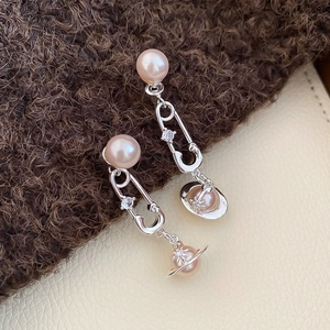 Détail de boucles d'oreilles en argent avec perles roses et charms planètes