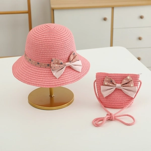 Detailed texture of pink woven straw sun hat and matching crossbody bag with polka dot bow
