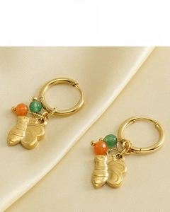 Détail de boucles d'oreilles abeille plaquées or 18k avec perles sur fond de soie