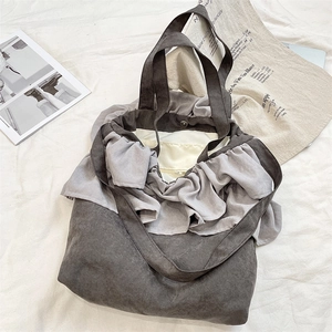Detail view of large grey tote bag featuring ruffled edges and magnetic snap closure