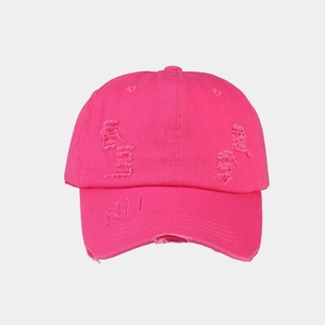 Close-up of distressed rose pink cotton baseball cap featuring street style frayed holes