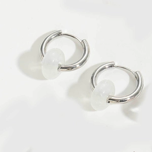 Macro shot of silver hoop earrings with translucent white stone pendants and clip closure
