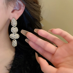 Detail of silver hammered drop earrings on model showing textured metallic layers