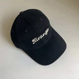 Detailed view of the Hiranga white script embroidery on a black cotton baseball cap