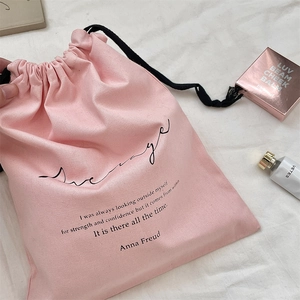 Detailed shot of pink canvas drawstring bag with printed quote and black cord closure
