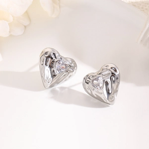 Macro shot of silver heart earrings with lava texture and centered sparkling zircon stone