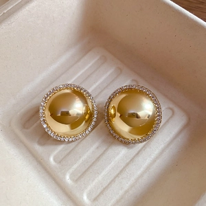 Macro shot of gold-plated domed stud earrings with shimmering crystal accents