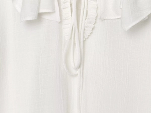 Detail van witte V-hals blouse met ruisranden en fijne trekkoordjes aan de kraag
