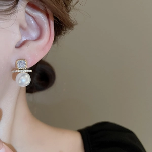 Detail of square zircon and pearl earring worn by model showing gold plated finish