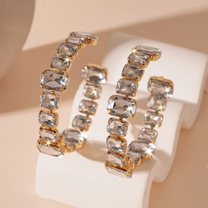 Macro detail of luxury gold hoop earrings with sparkling square rhinestones on display