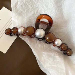 Détail de la pince à cheveux en acrylique ambré avec perles factices et ornements