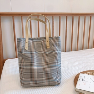 Detail of vintage plaid tote bag with cream leather handles and rivet reinforcements