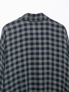 Dettaglio del colletto posteriore e delle cuciture di una camicia a quadri blu