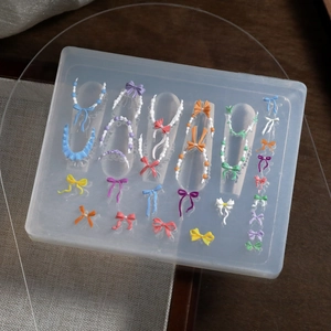 Macro detail of translucent 3D silicone nail art mold featuring bow tie and bead patterns