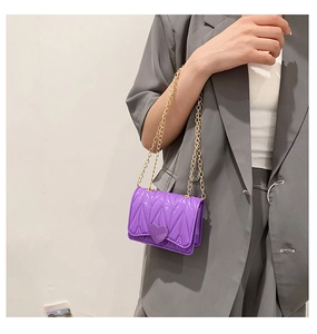 Macro detail of purple silicone heart bag with gold chain strap on grey blazer