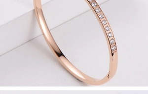 Detail of rose gold bangle with pave set cubic zirconia crystals and hidden clasp