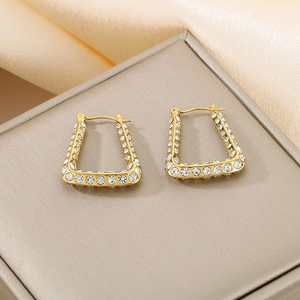 Detailed close-up of golden U-shaped geometric earrings set with sparkling zircon gems