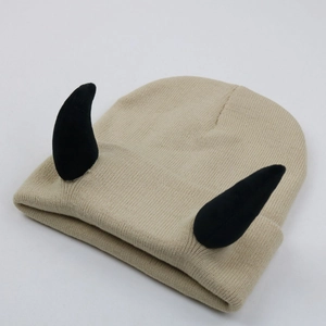 Beige knitted beanie with black devil horns for a fun and warm winter style