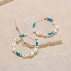 Macro shot of Bohemian hoop earrings with baroque pearls and blue turquoise beads