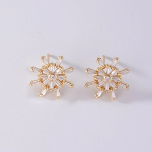 Macro detail of gold snowflake stud earrings featuring baguette and round zircon stones
