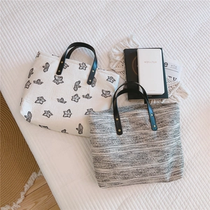 Détail de sacs cabas en toile avec broderie papillon et texture tweed sur fond blanc