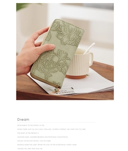 Detail view of long sage green wallet featuring embossed rose floral texture and gold zipper
