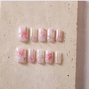 Detailed macro view of cherry blossom press-on nails with pink petals and gold foil details