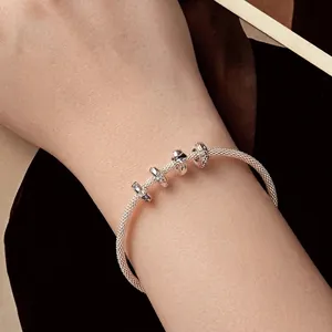 Classic 925 sterling silver snake chain bracelet with elegant charms on a woman wrist