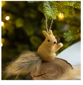 Detailed view of plush squirrel ornament with pinecone on Christmas tree branch
