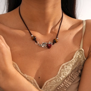 Close-up of vintage sweater chain featuring strawberry pendant and tiger eye beads