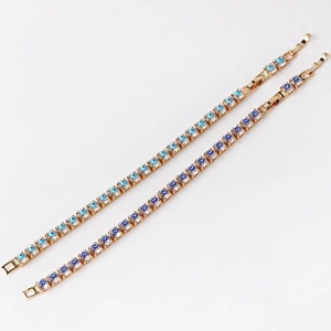 Detail of gold chain bracelets with blue zircon evil eye charms on a white background