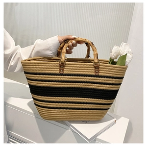 Detail of woven straw handbag with bamboo handles and black striped decorative accents
