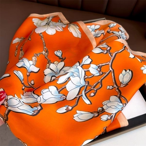 Detail of silk scarf with orange magnolia print and premium hand-rolled edges