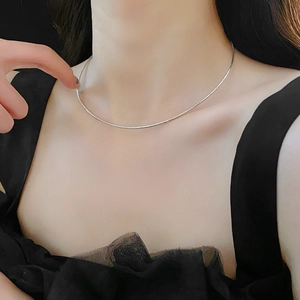Detail of silver minimalist snake chain choker necklace on model with black dress