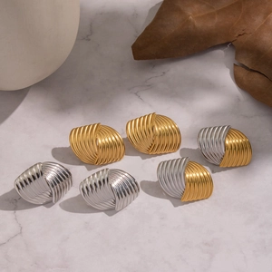 Moderne geometrische Spiralohrstecker in Gold und Silber auf Marmorhintergrund