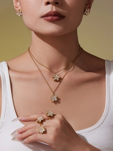 Dettaglio del set di gioielli con fiori a quattro foglie dorati e cristalli luccicanti