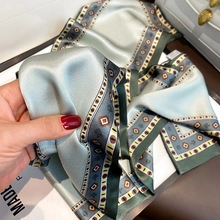 Detail of silk-feel scarf with geometric prints, mint green edges, and Made in France label