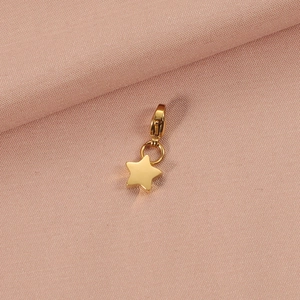 Close-up of a polished gold star pendant with a lobster clasp on a pink fabric background