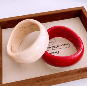 Gros plan d'un ensemble de bracelets en acrylique marbre ivoire et rouge dans leur boîte