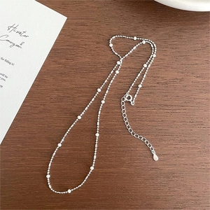Elegant 925 sterling silver necklace with white beads on a rustic dark wood background